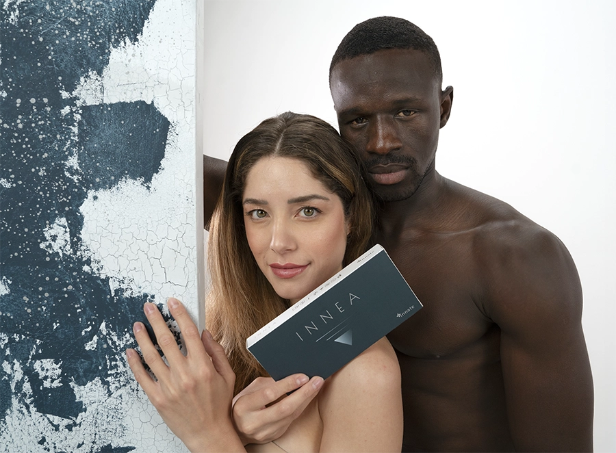 Woman holding INNEA Classic product box in front of a man, both posing closely and confidently against a textured blue and white background.
