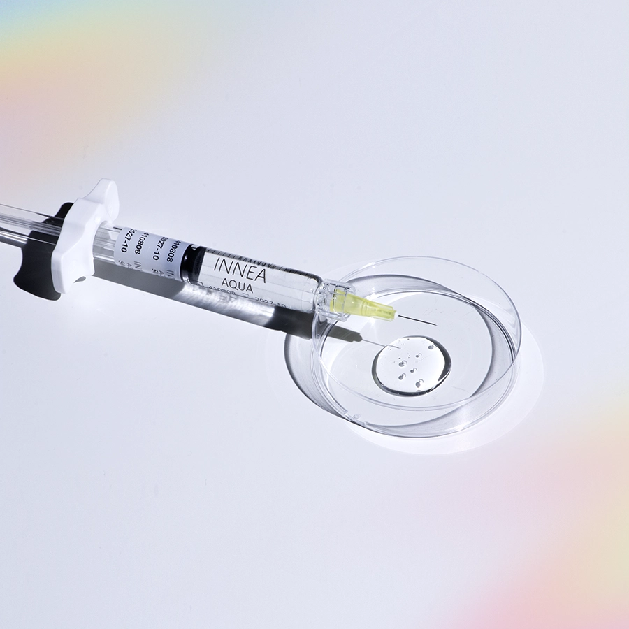 Close-up of an INNEA Aqua injectable syringe placed beside a petri dish, symbolizing purity, hydration, and scientific precision in aesthetic medicine.