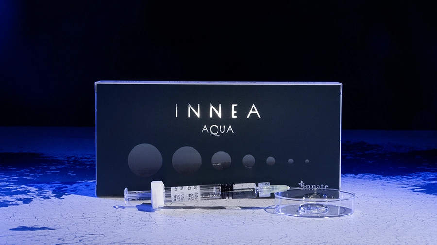 INNEA Aqua product packaging with syringe and petri dish under blue-toned lighting. Conveys essential care and scientific rigor in aesthetic treatments.