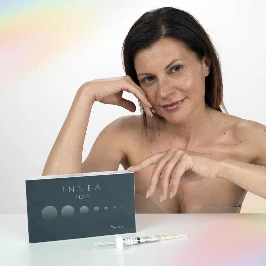 Smiling woman presenting the INNEA Aqua product box with syringe in front, expressing hydration and confidence in aesthetic care.