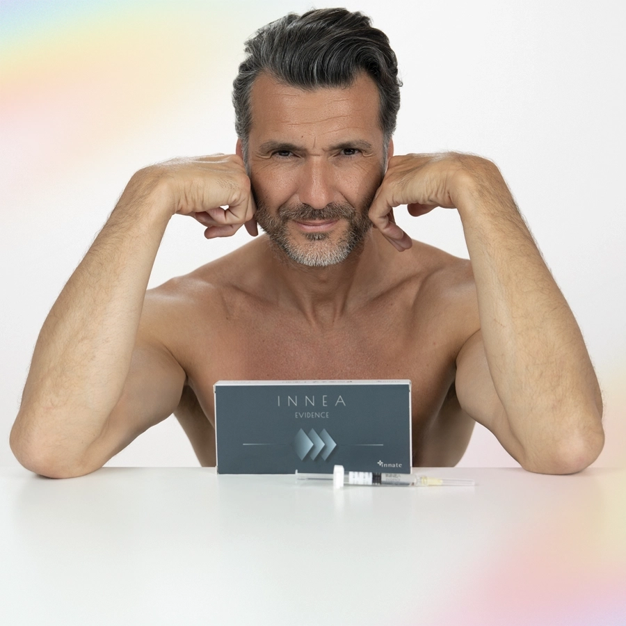 Confident mature man posing with INNEA Evidence product box and syringe. Reflects aesthetic self-care and rejuvenation for men.